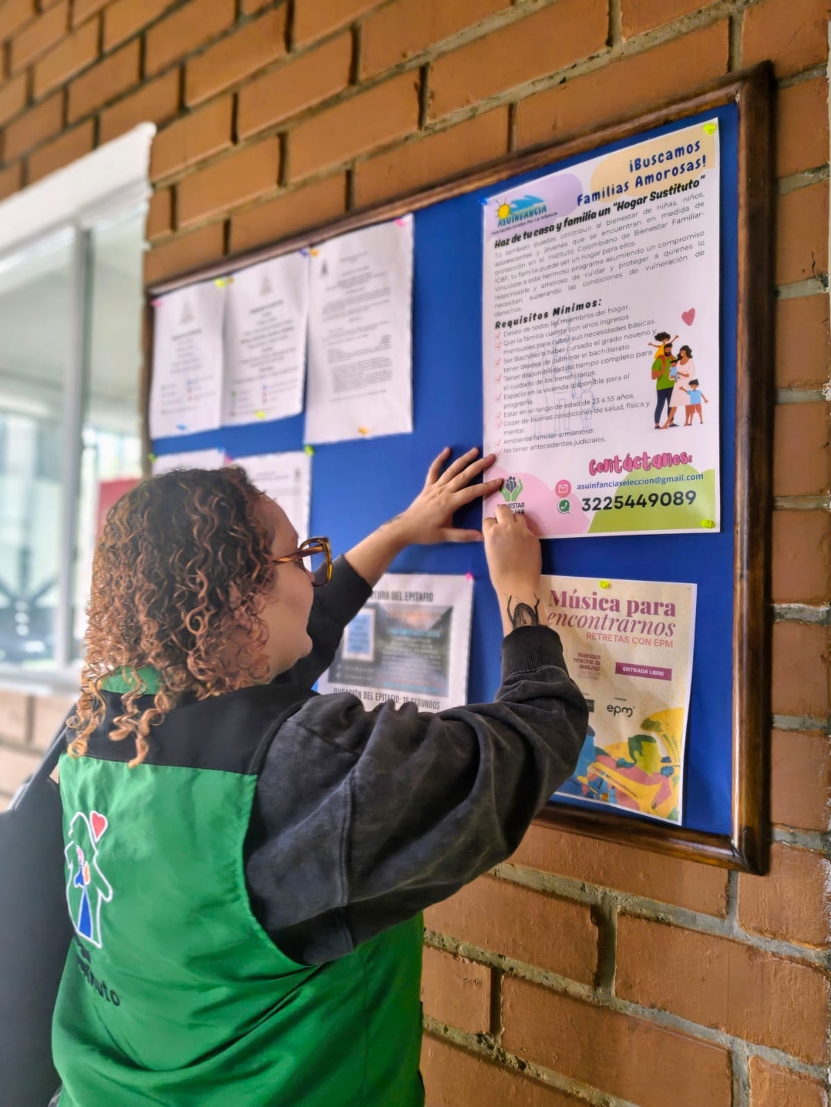 Funcionaria de ASUINFANCIA publicando información en cartelera comunitaria